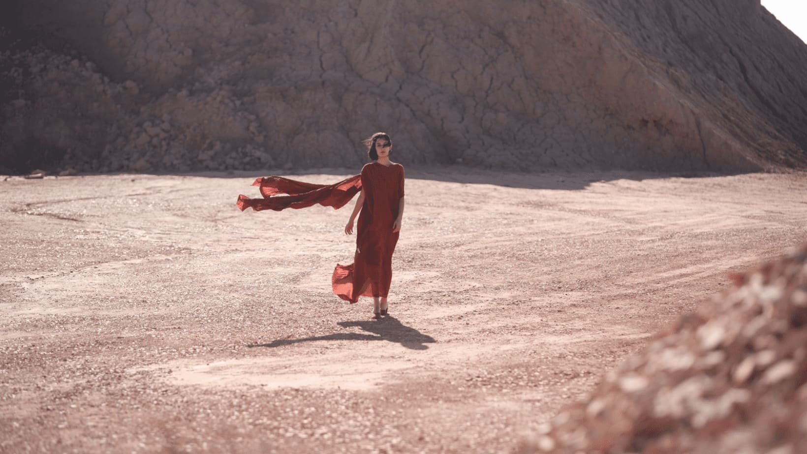 Woman walking in the desert, dress blowing in the wind