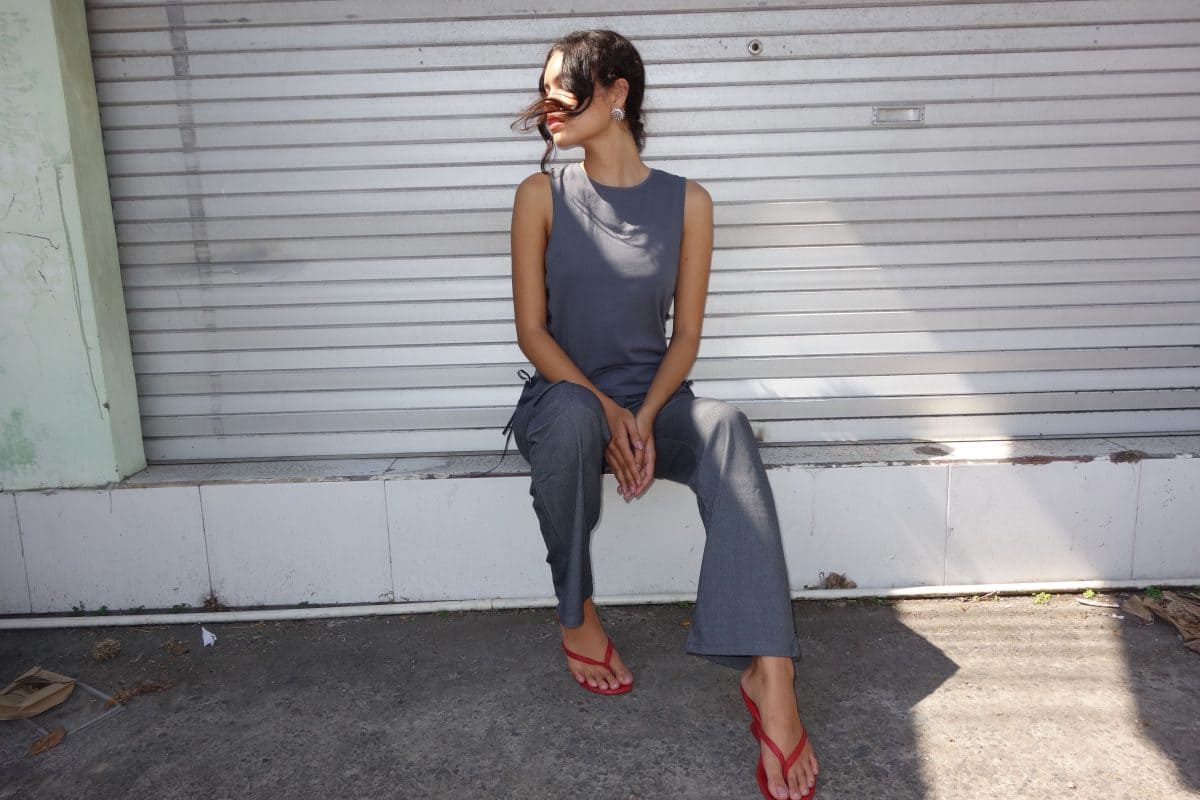 Woman sitting on side of street wearing a grey pantsuit