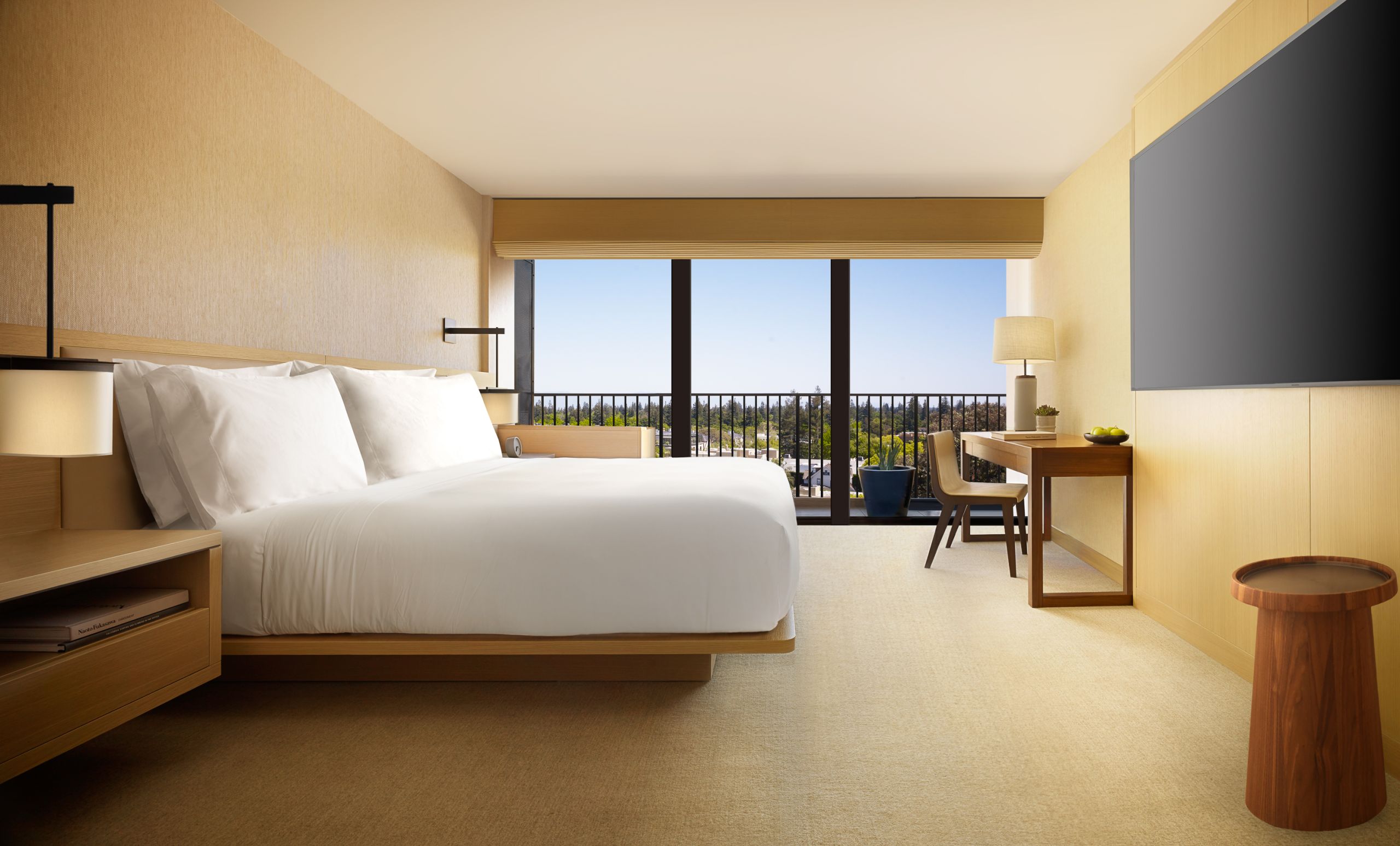 Nobu king room that showcases two sidetables, a desk and tv. The room overlooks the balcony with a beautiful view.