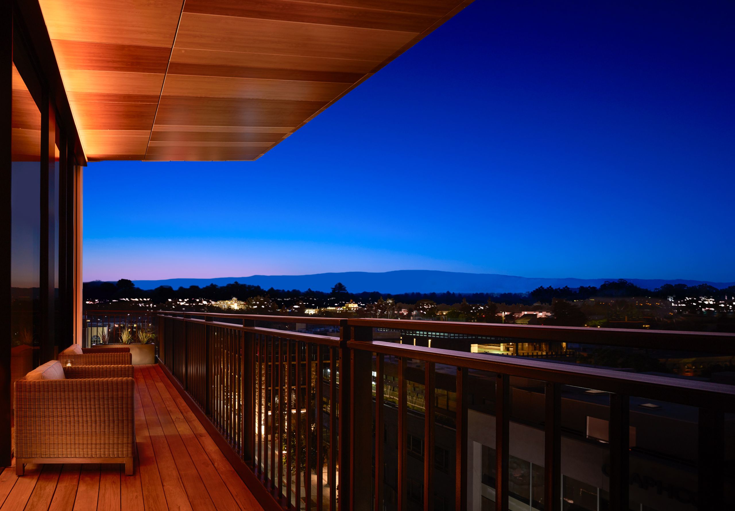 Nobu view of balcony at night. Two seats share a view of the city.