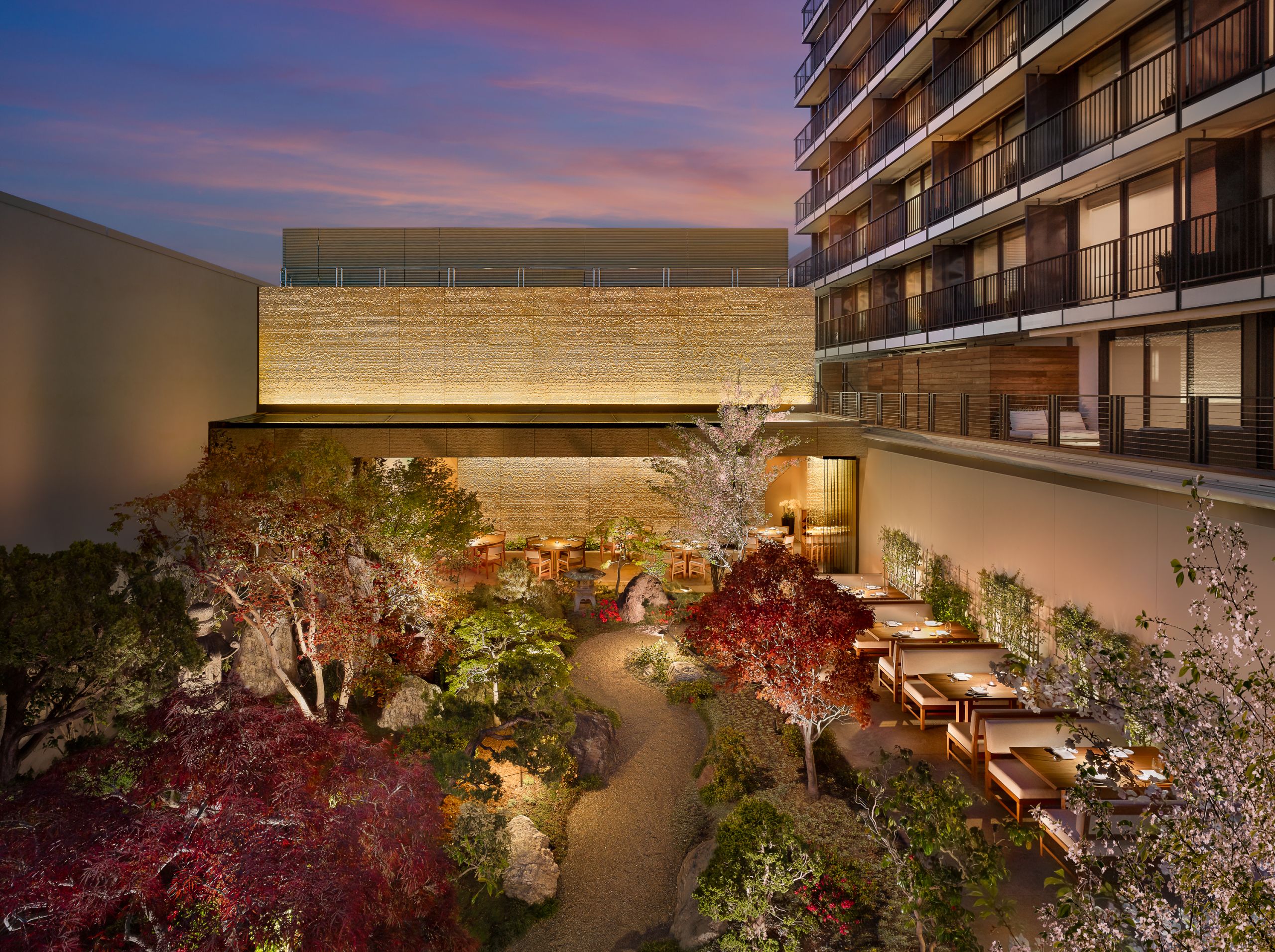 Nobu garden overlooks seating area and tables are lit up with light. The balcony's show the view of the pink sky at night.
