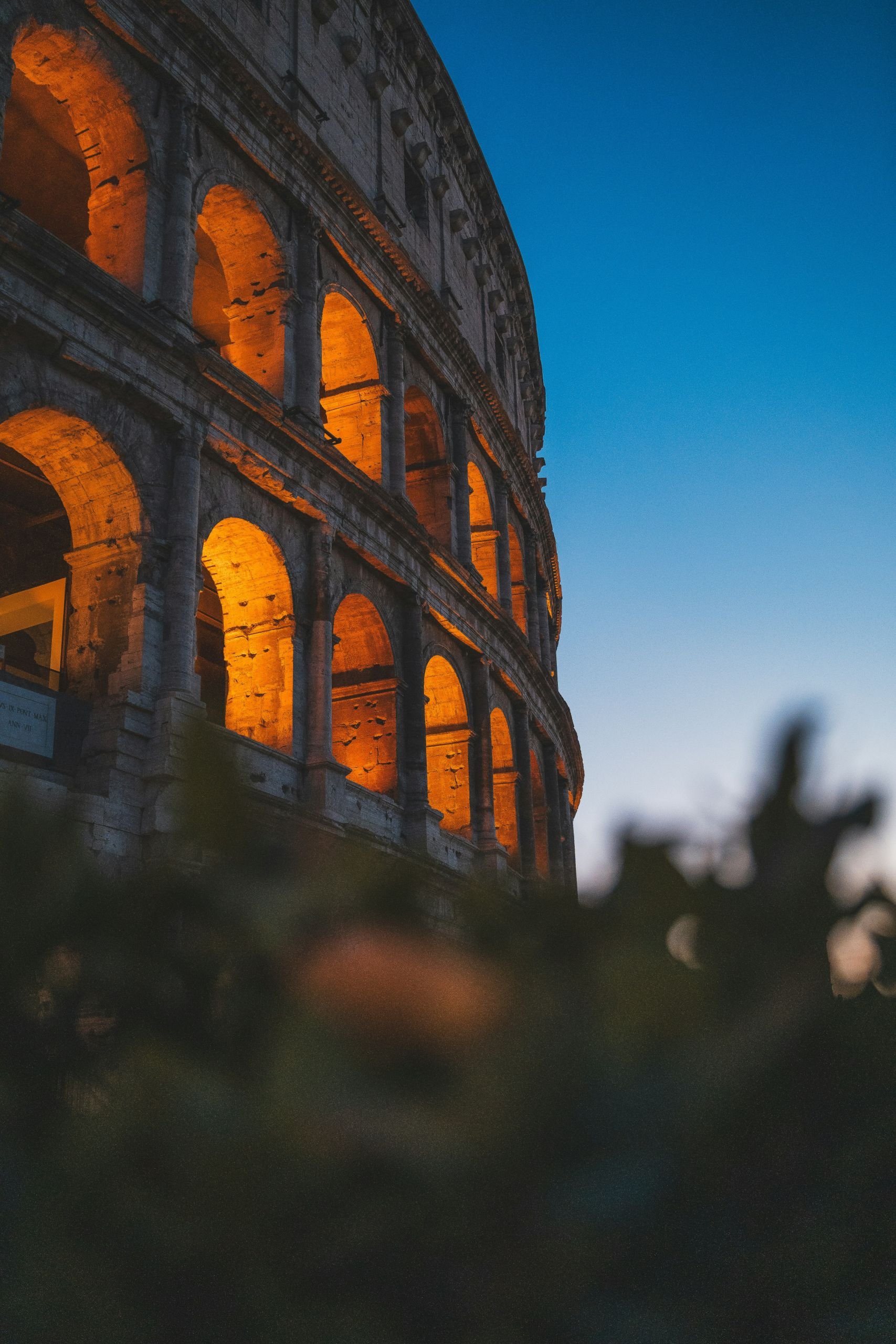 The coliseum at night with lights shining from the window area in Rome