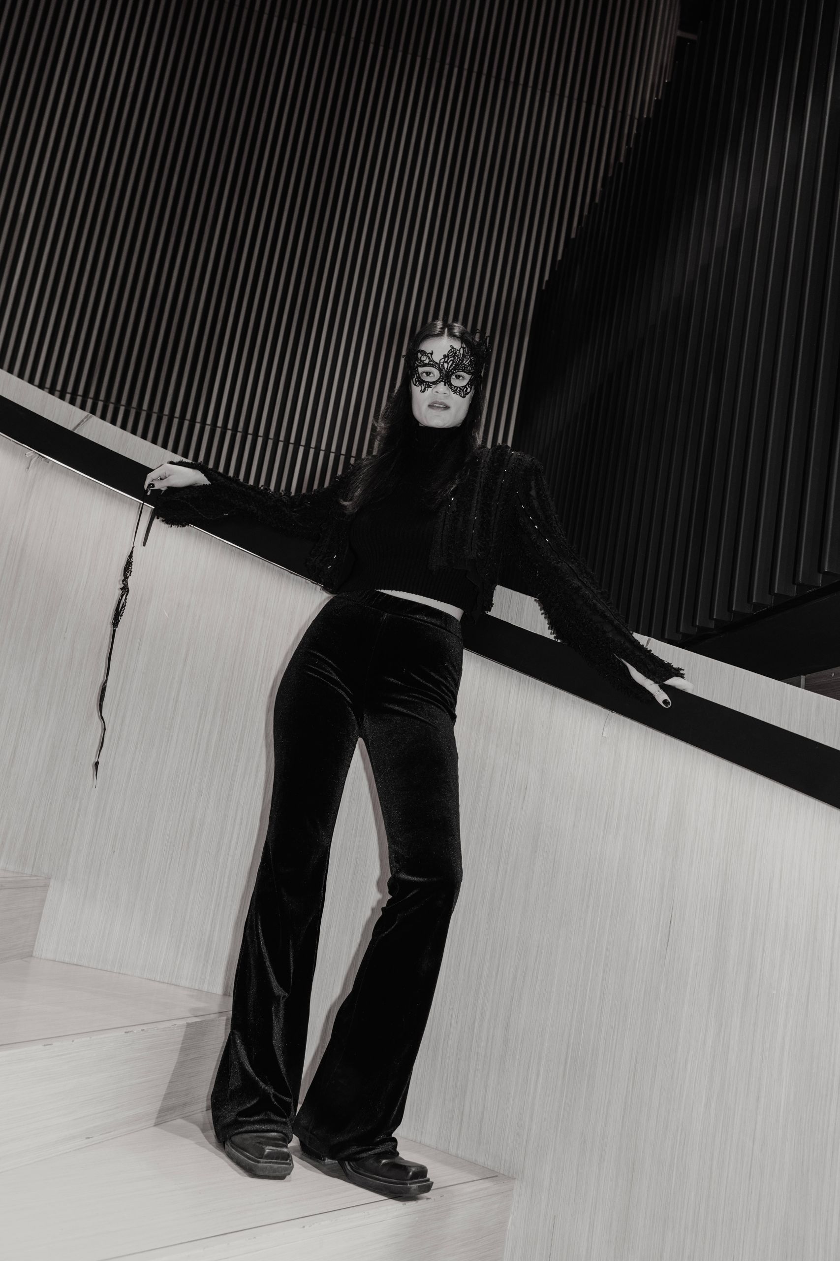 A woman elegantly poses on a staircase in a striking black and white photograph